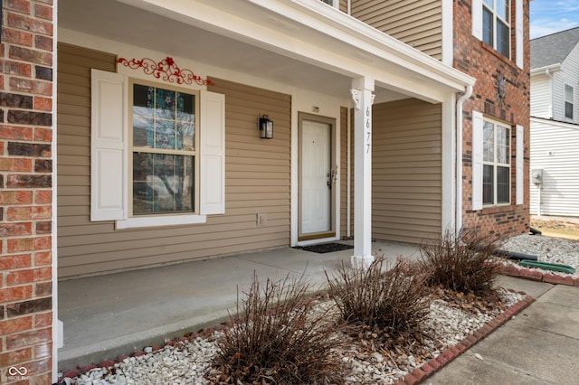 property entrance featuring a porch and brick siding