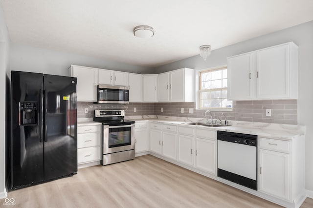 kitchen featuring light wood finished floors, white cabinetry, stainless steel appliances, and a sink