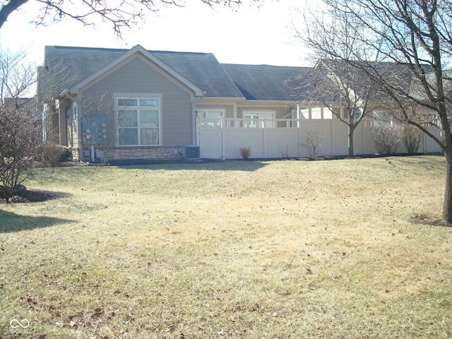 view of front of property with a front yard, stone siding, and cooling unit