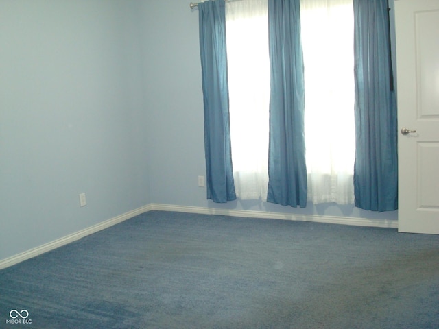 carpeted spare room featuring a healthy amount of sunlight and baseboards