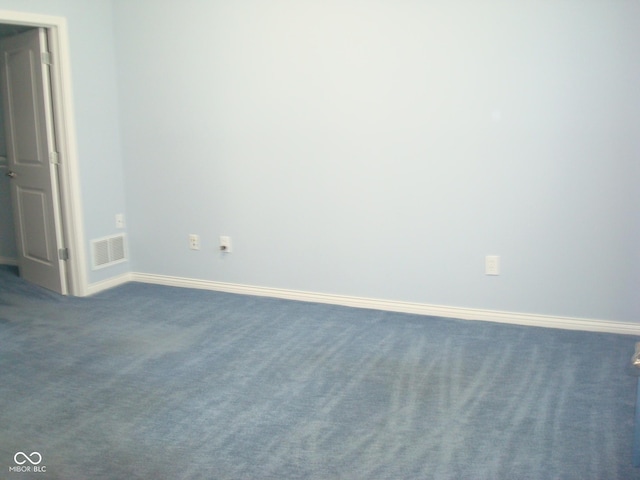 spare room featuring baseboards, visible vents, and dark carpet