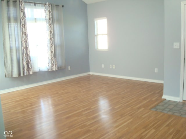 spare room with baseboards and wood finished floors