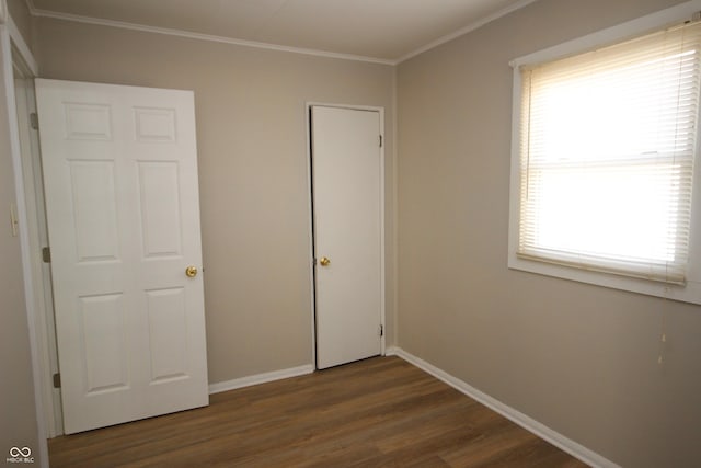 unfurnished bedroom with ornamental molding, dark wood-style flooring, and baseboards