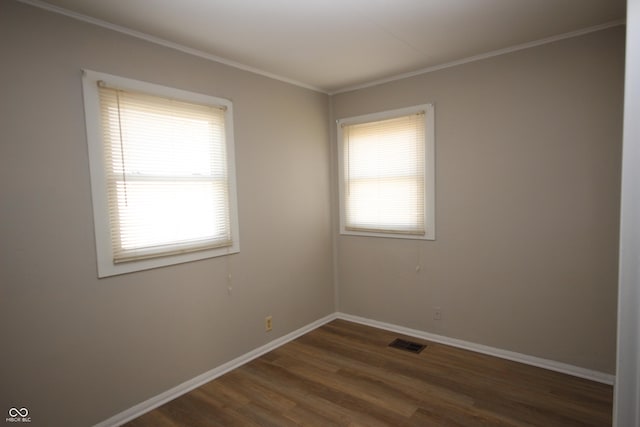 unfurnished room with a wealth of natural light, wood finished floors, visible vents, and baseboards