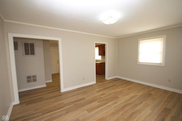 unfurnished bedroom featuring light wood finished floors, ornamental molding, and visible vents