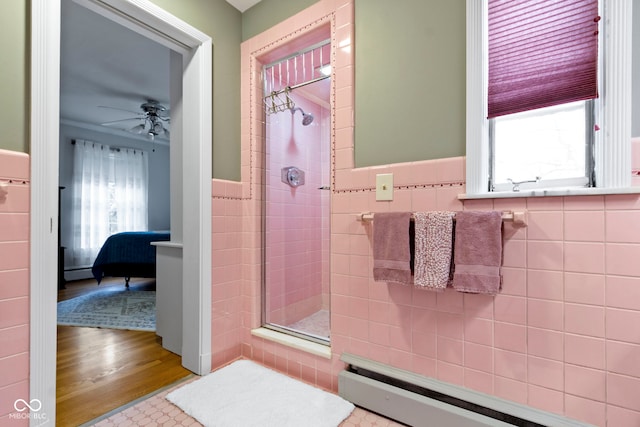 bathroom with a baseboard heating unit, baseboard heating, a stall shower, wood finished floors, and tile walls