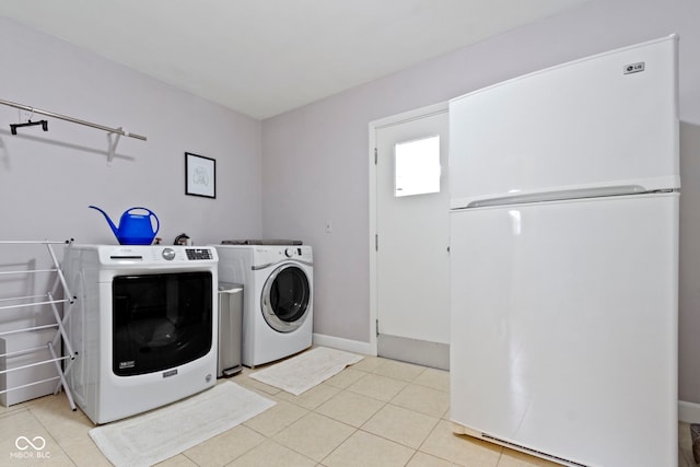 clothes washing area featuring light tile patterned floors, washing machine and dryer, and laundry area