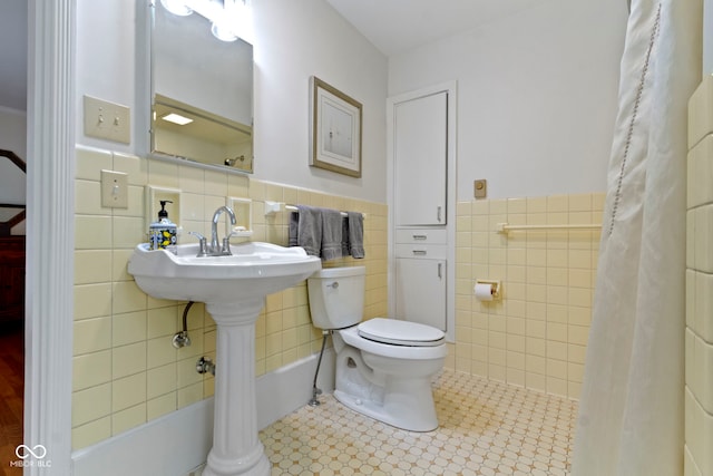 bathroom with tile walls, toilet, and a wainscoted wall