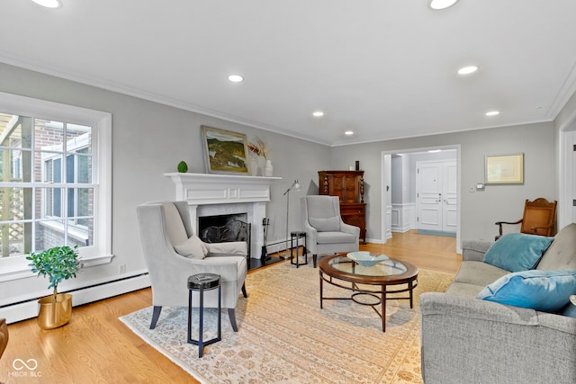 living room with light wood finished floors, baseboard heating, a fireplace, and crown molding