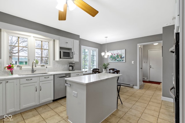 kitchen with a kitchen island, a baseboard heating unit, decorative backsplash, appliances with stainless steel finishes, and a sink