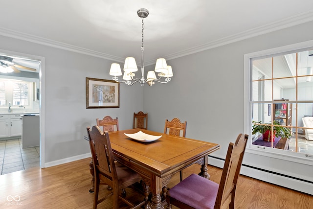 dining area featuring a notable chandelier, crown molding, light wood finished floors, a baseboard radiator, and baseboards