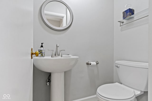 half bathroom featuring baseboards and toilet