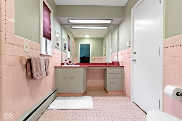 bathroom with a wainscoted wall, baseboard heating, tile walls, and vanity