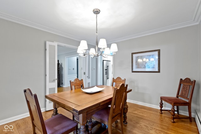 dining room with a baseboard heating unit, crown molding, light wood-style floors, and baseboards