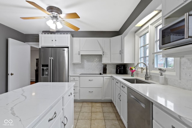 kitchen featuring white cabinets, backsplash, appliances with stainless steel finishes, and a sink