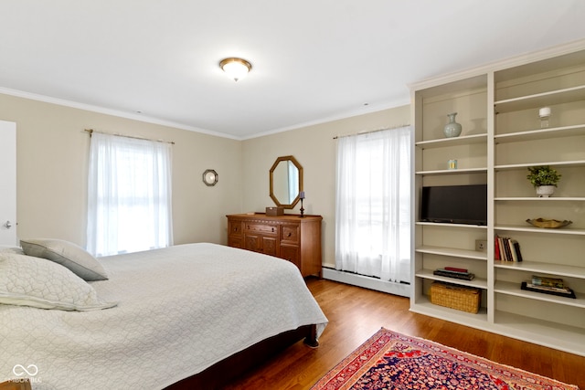 bedroom with baseboard heating, multiple windows, crown molding, and wood finished floors