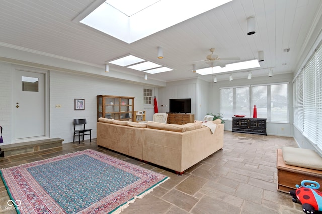 living room featuring visible vents, crown molding, stone tile floors, a skylight, and a ceiling fan