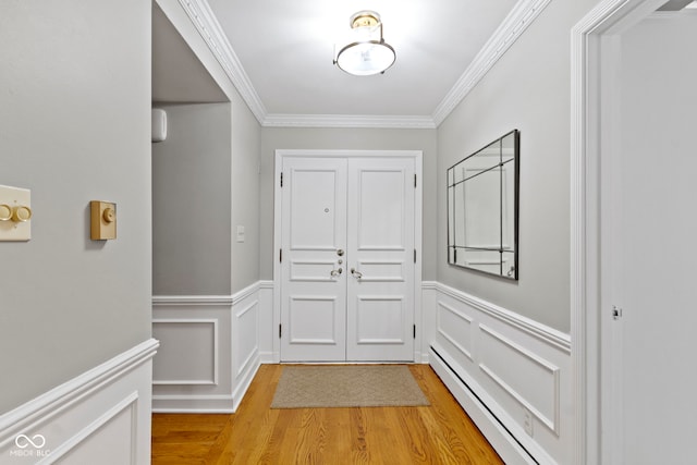 doorway with wainscoting, a baseboard radiator, light wood-type flooring, and ornamental molding