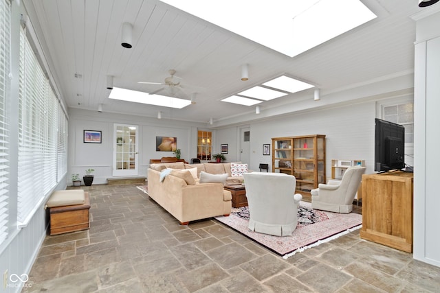 living area featuring wood ceiling, ornamental molding, stone tile floors, a skylight, and a ceiling fan