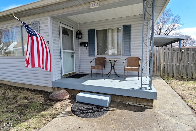 doorway to property with covered porch and fence