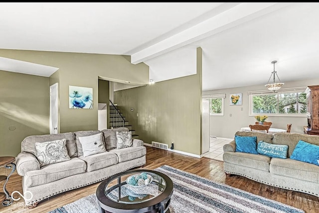 living room featuring visible vents, lofted ceiling with beams, wood finished floors, stairway, and baseboards