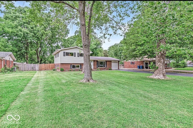 view of front facade with aphalt driveway, fence, a front yard, a garage, and brick siding