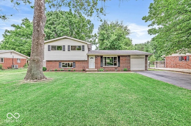 split level home with aphalt driveway, an attached garage, brick siding, and a front yard