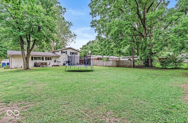 view of yard featuring a patio, a trampoline, and fence