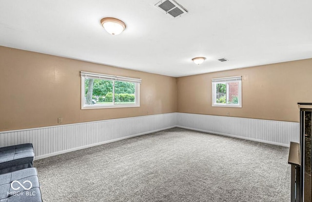 carpeted spare room with a wainscoted wall and visible vents