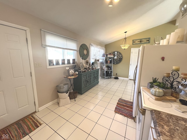 kitchen featuring vaulted ceiling, decorative light fixtures, light tile patterned flooring, and baseboards