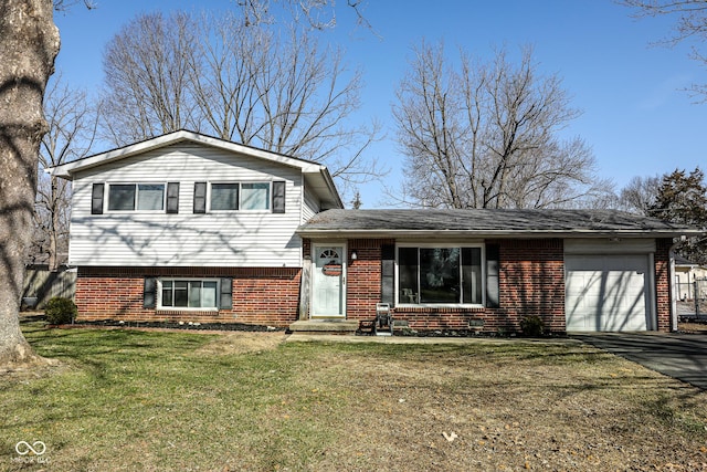 split level home featuring brick siding, a front yard, aphalt driveway, and a garage