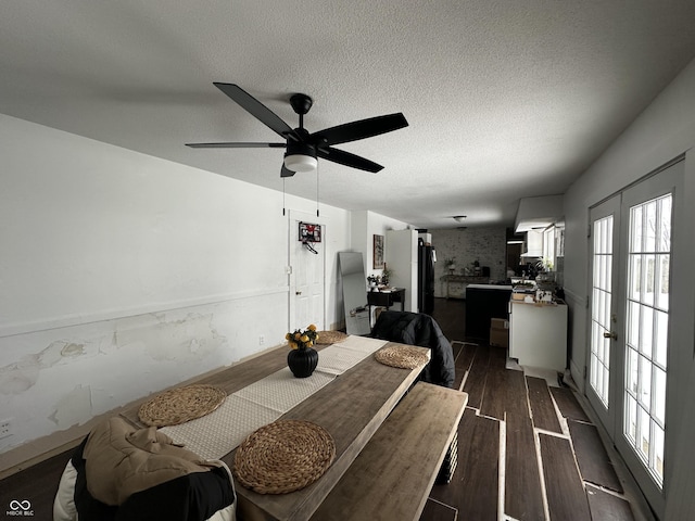 dining space featuring dark wood-style flooring, ceiling fan, a textured ceiling, and french doors