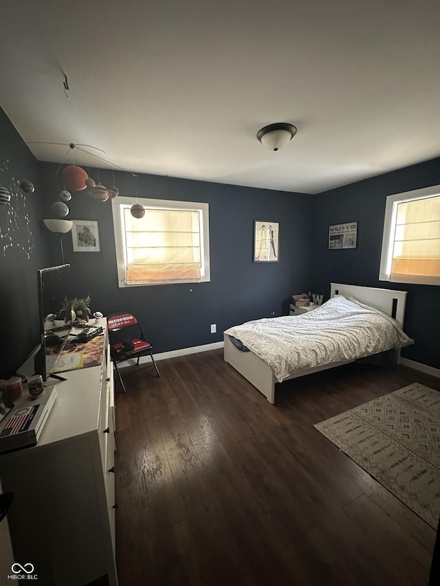 bedroom featuring multiple windows, baseboards, and wood finished floors