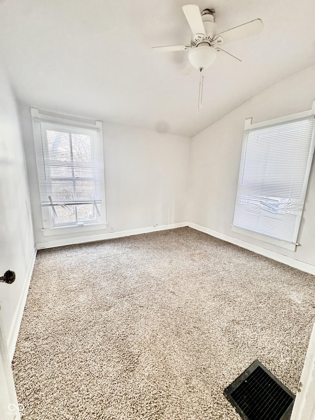 carpeted spare room featuring visible vents, baseboards, and ceiling fan