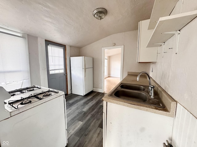 kitchen featuring white appliances, dark wood-style flooring, a sink, vaulted ceiling, and a textured ceiling