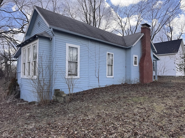 view of side of property featuring roof with shingles and a chimney