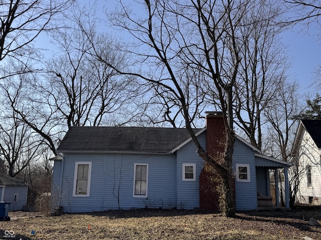 view of side of property featuring roof with shingles and a chimney