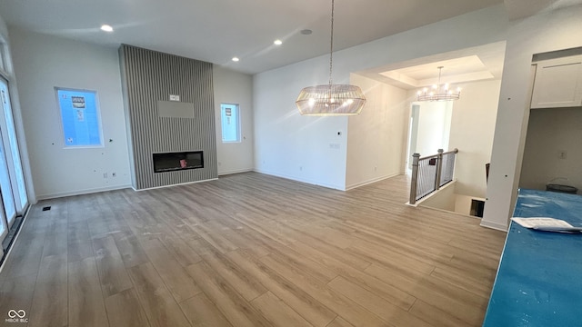 unfurnished living room featuring a large fireplace, light wood finished floors, baseboards, and recessed lighting