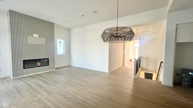 unfurnished living room featuring baseboards, wood finished floors, and a glass covered fireplace