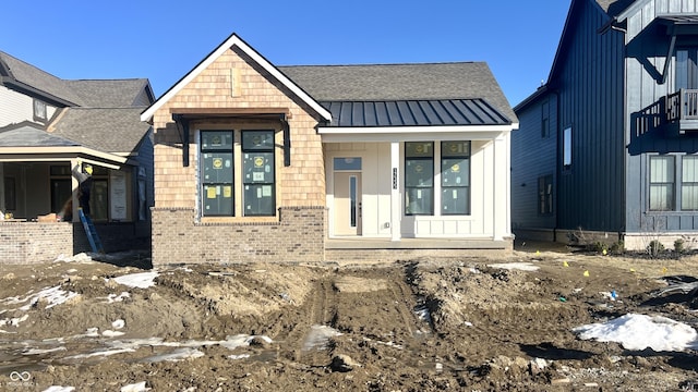 view of front of home with a standing seam roof, metal roof, and brick siding