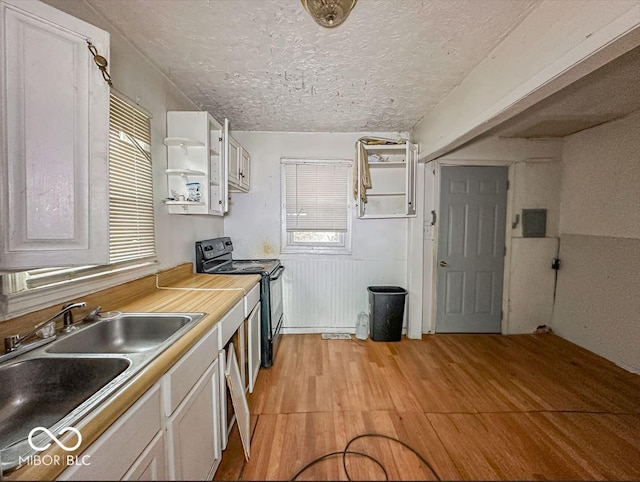 kitchen with black / electric stove, a textured ceiling, open shelves, light wood-style floors, and a sink