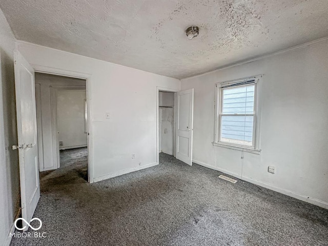 unfurnished bedroom with visible vents, carpet flooring, and a textured ceiling