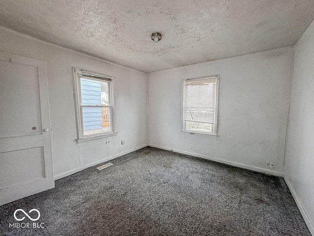 carpeted empty room with a textured ceiling, baseboards, and visible vents