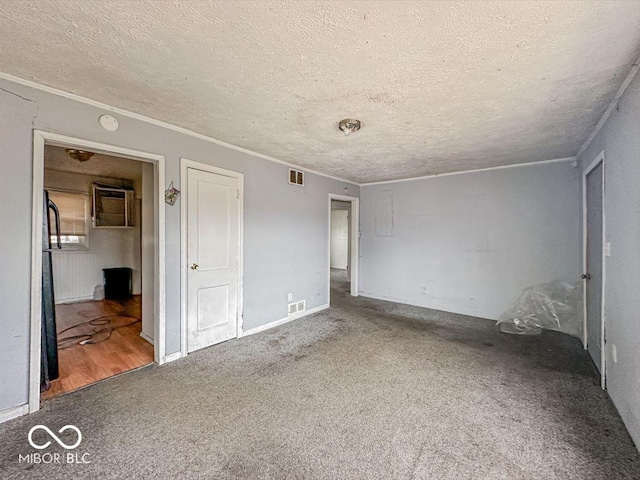 unfurnished bedroom with a textured ceiling, carpet flooring, ornamental molding, and visible vents
