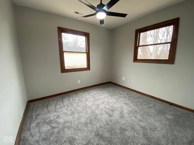 carpeted spare room with visible vents, baseboards, and a ceiling fan