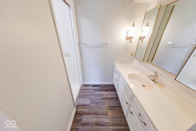 bathroom with visible vents, vanity, baseboards, and wood finished floors