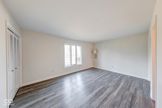 unfurnished bedroom with visible vents, a closet, baseboards, and wood finished floors