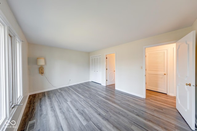 spare room featuring visible vents, baseboards, and wood finished floors