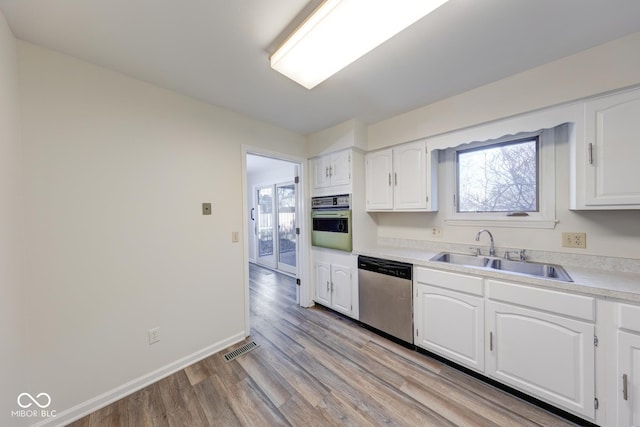 kitchen with visible vents, white oven, stainless steel dishwasher, white cabinetry, and a sink