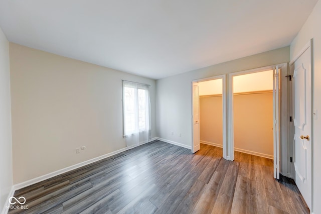 unfurnished bedroom featuring dark wood finished floors, visible vents, and baseboards